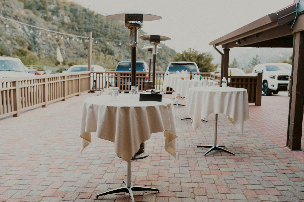 Linen cocktail tables and heat lamps on the creekside patio with the mountain behind